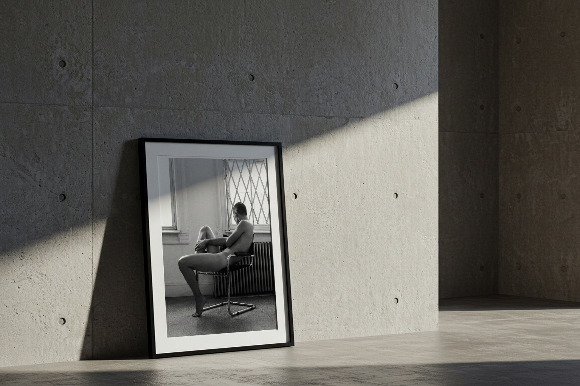 Black and White Nude photography of a male, framed laying against a wall