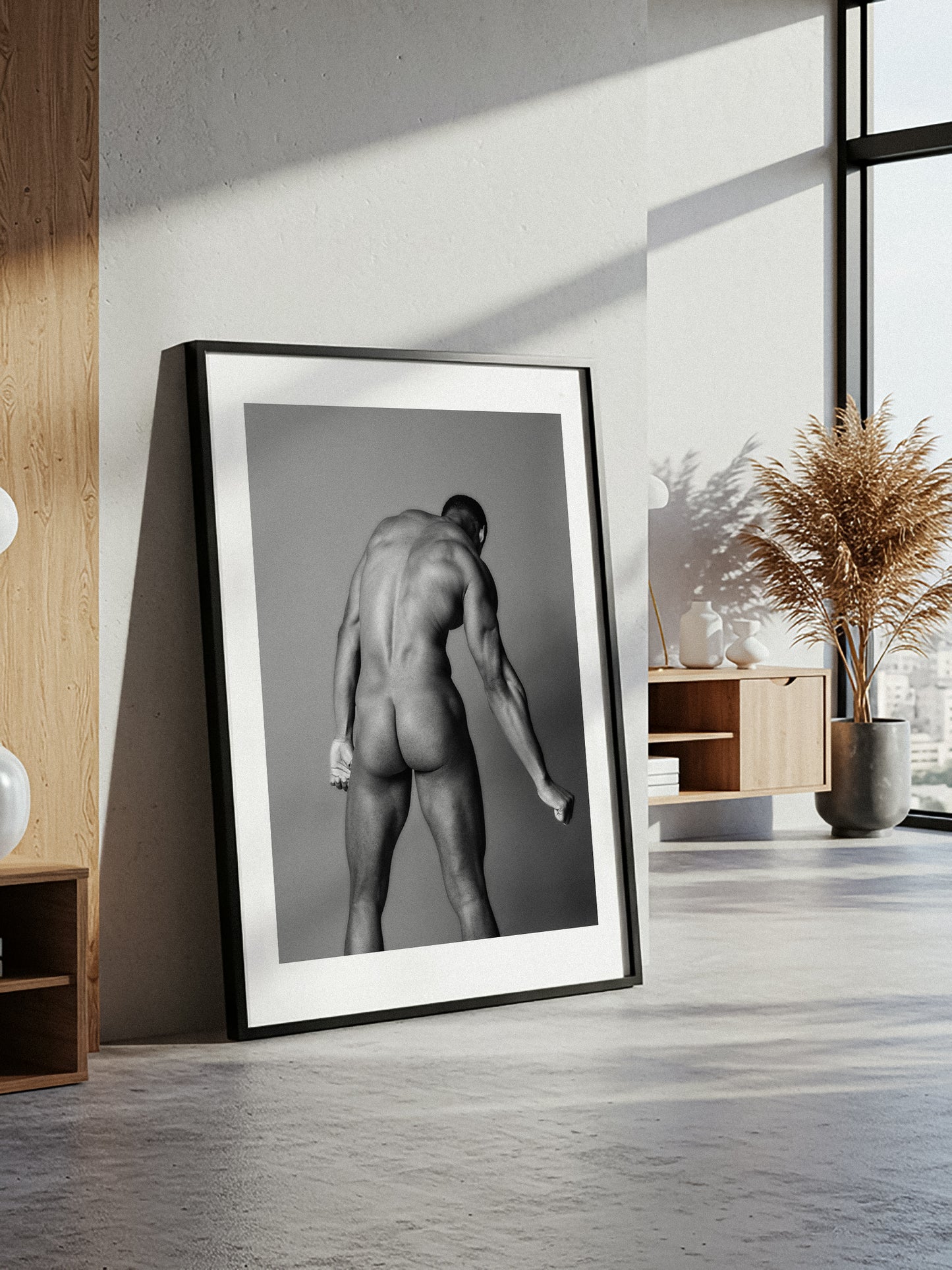 Framed black and white photography print of a nude figure in a modern room with natural light.