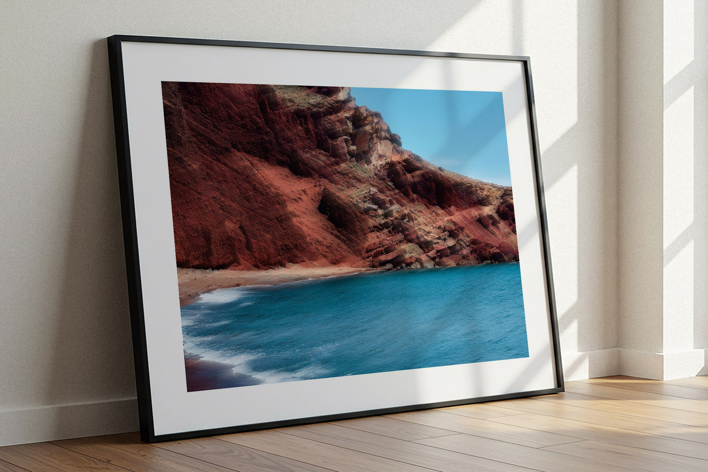Fine art photography of a coastal landscape with ethereal red cliffs and blue water on a white wall