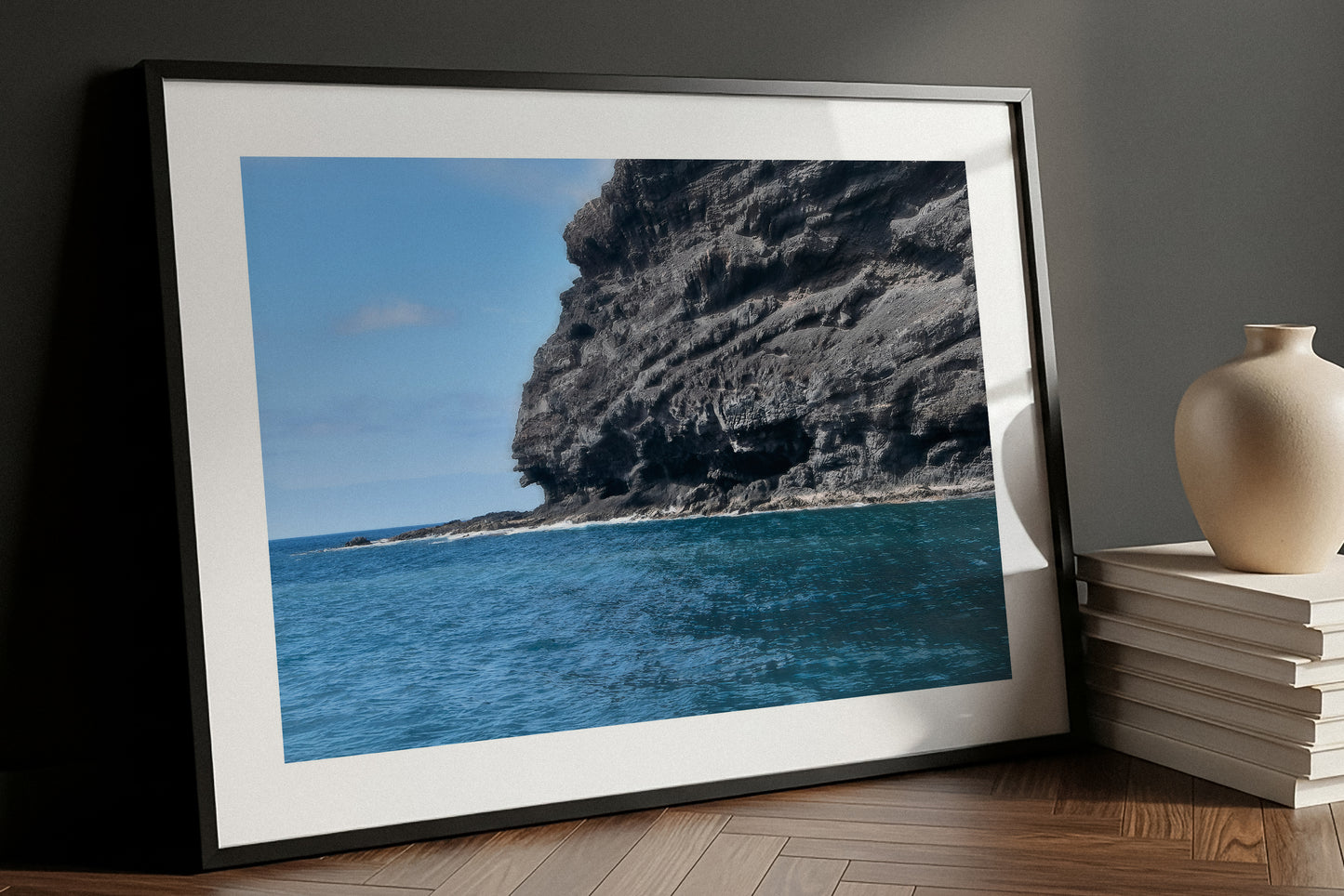 Framed fine art print of a coastal scene with a rocky cliff and blue sky.