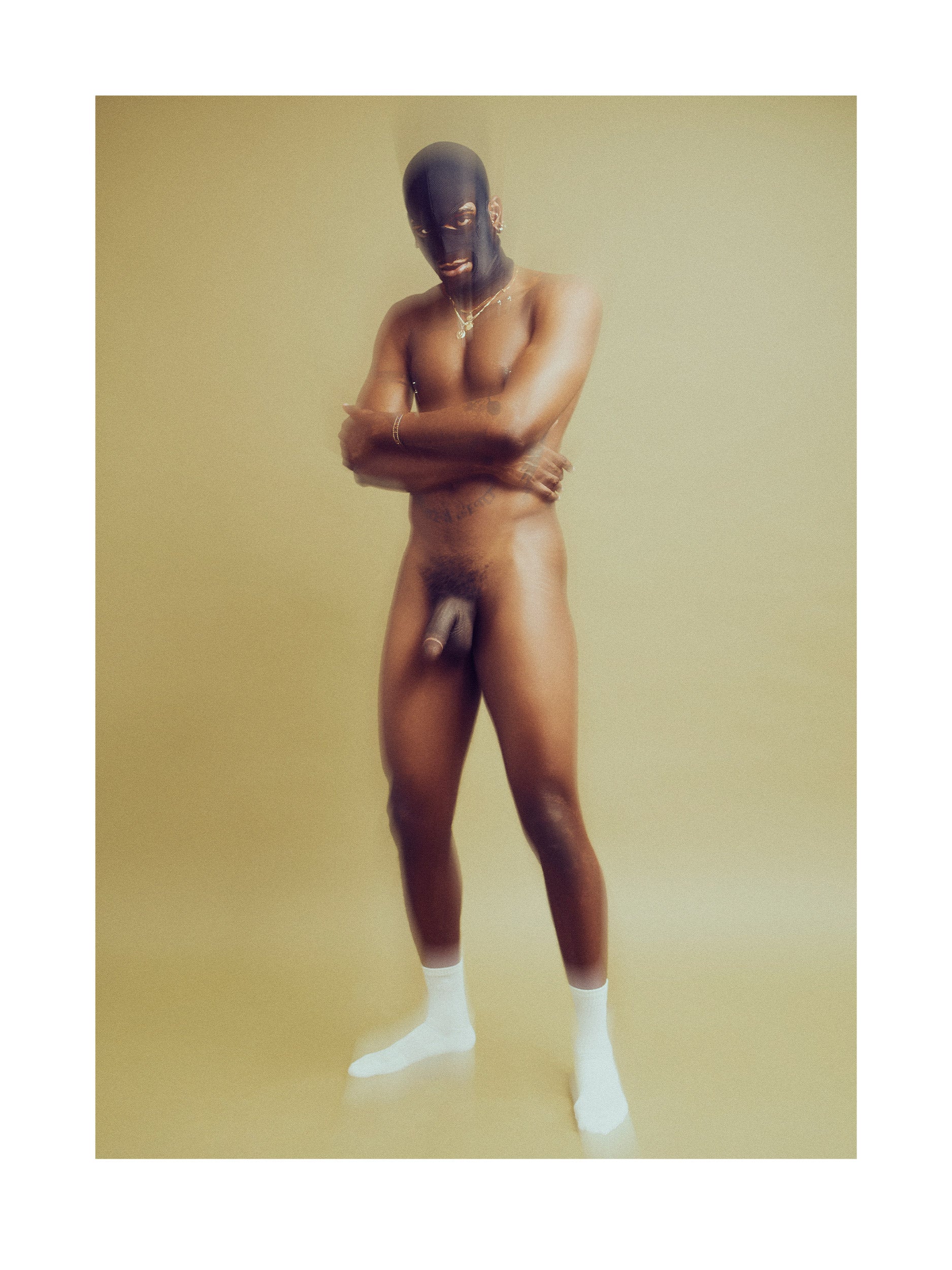 Fine Art Photograph of a nude man wearing a black mask and white socks on a green background