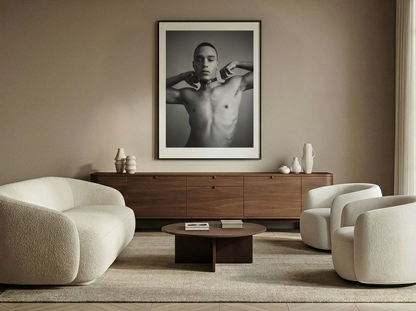 Modern living room with a framed black and white portrait on the wall, wooden sideboard, and beige armchairs.