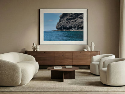 Modern living room with a large framed fine art picture of a volcanic coastal scene on the wall.