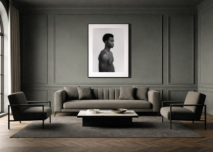 Modern living room with a gray sofa, chairs, and a framed black and white fine art portrait on the wall.
