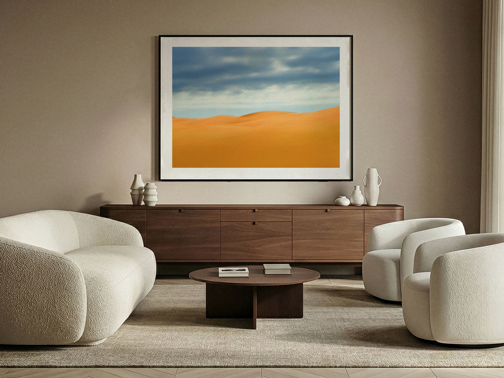 Modern living room with beige sofas, a wooden coffee table, and a fine art photograph of desert dunes landscape on the wall.