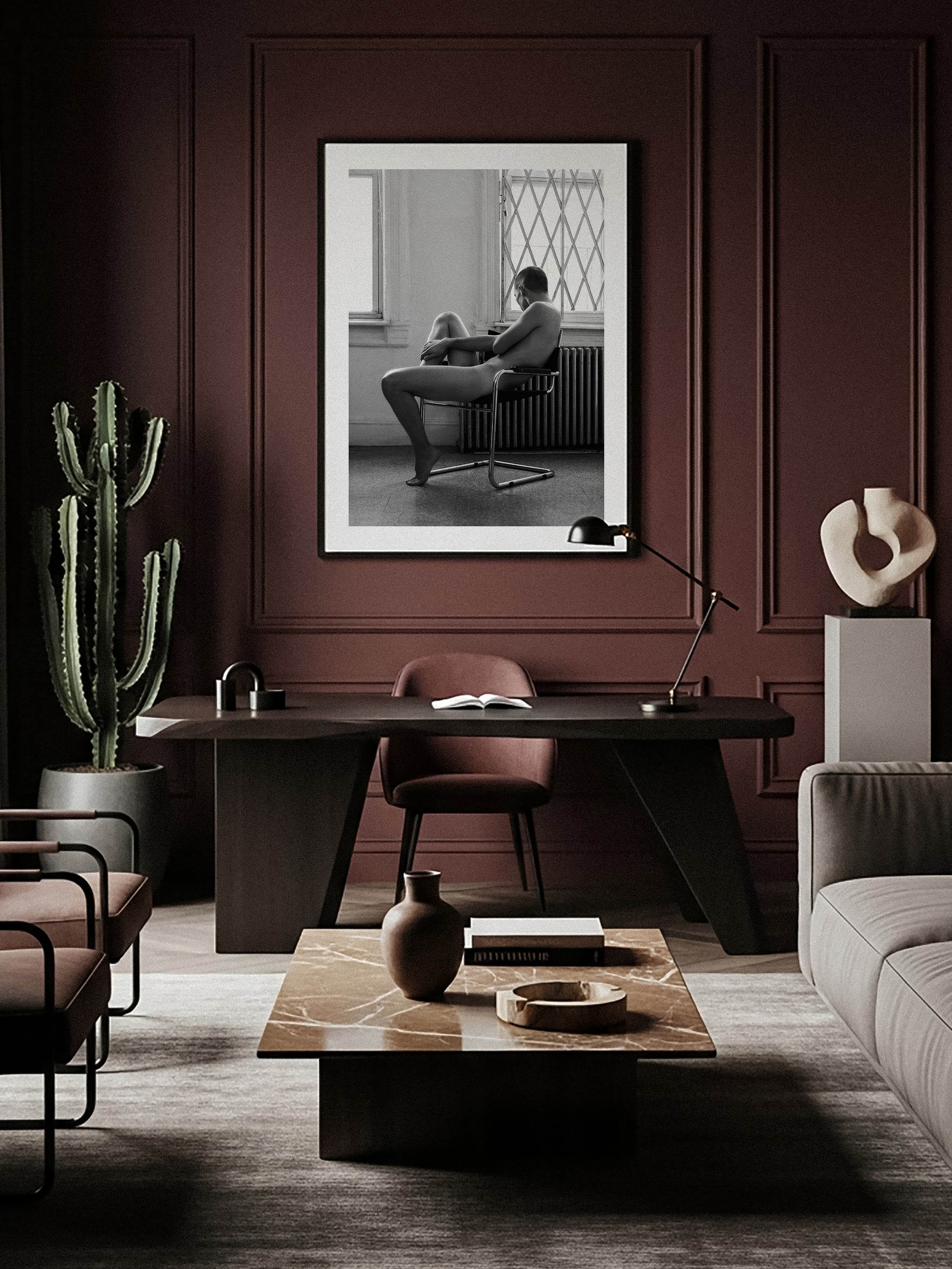 Modern interior with a dark wooden desk, chairs, and a cactus plant and fine art photography of a nude male sitting creating organic geometrical forms.