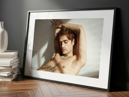 Framed fine art portrait of a shirtless man with tattoos leaning against a wall, placed on a wooden floor. Limited Edition, signed and numbered.